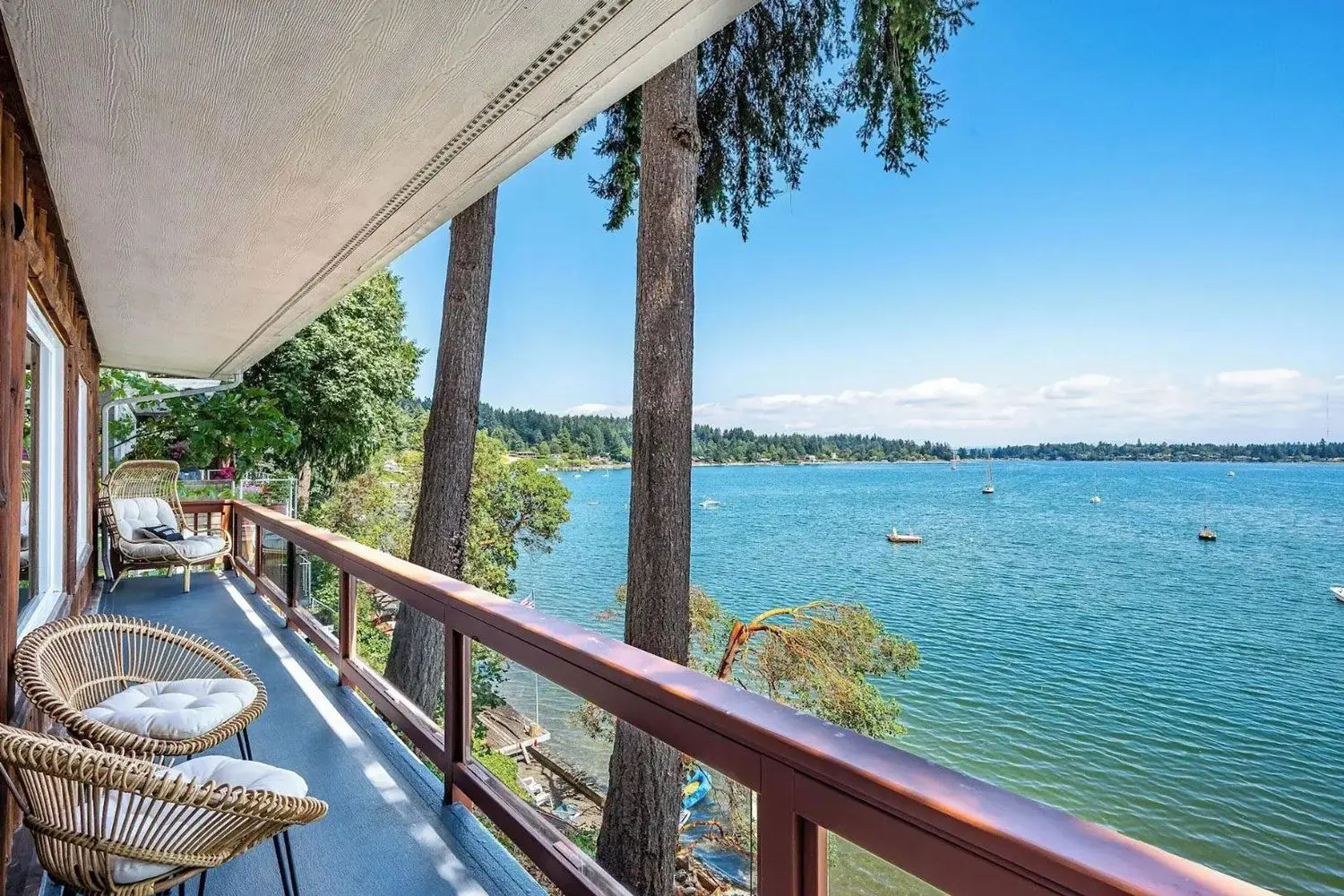 A balcony with chairs and tables overlooking the water.