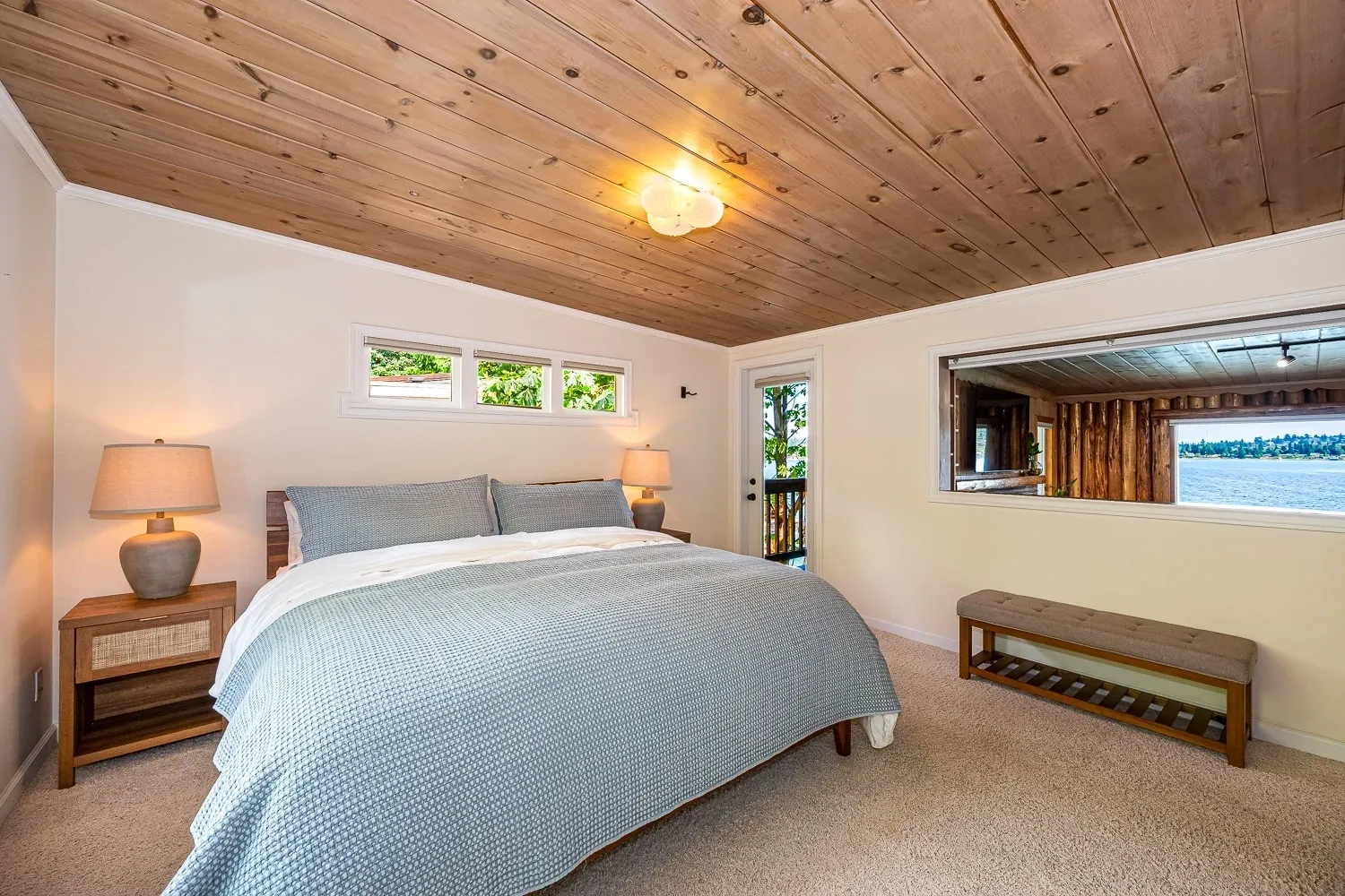 A bedroom with a bed, window and wooden ceiling.