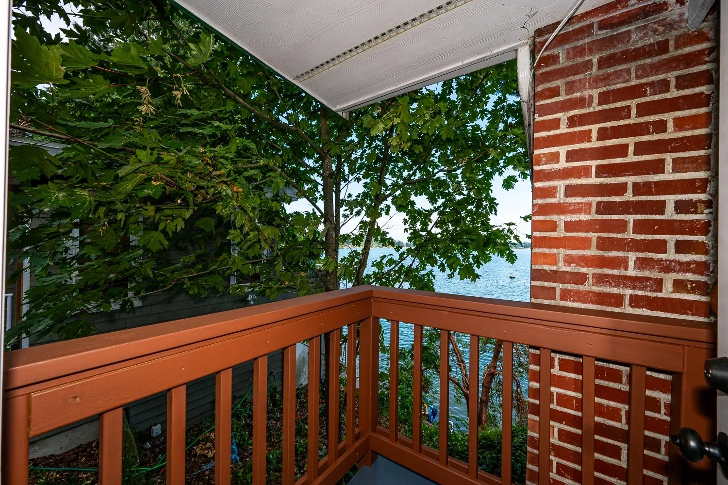 A balcony with a view of the water and trees.